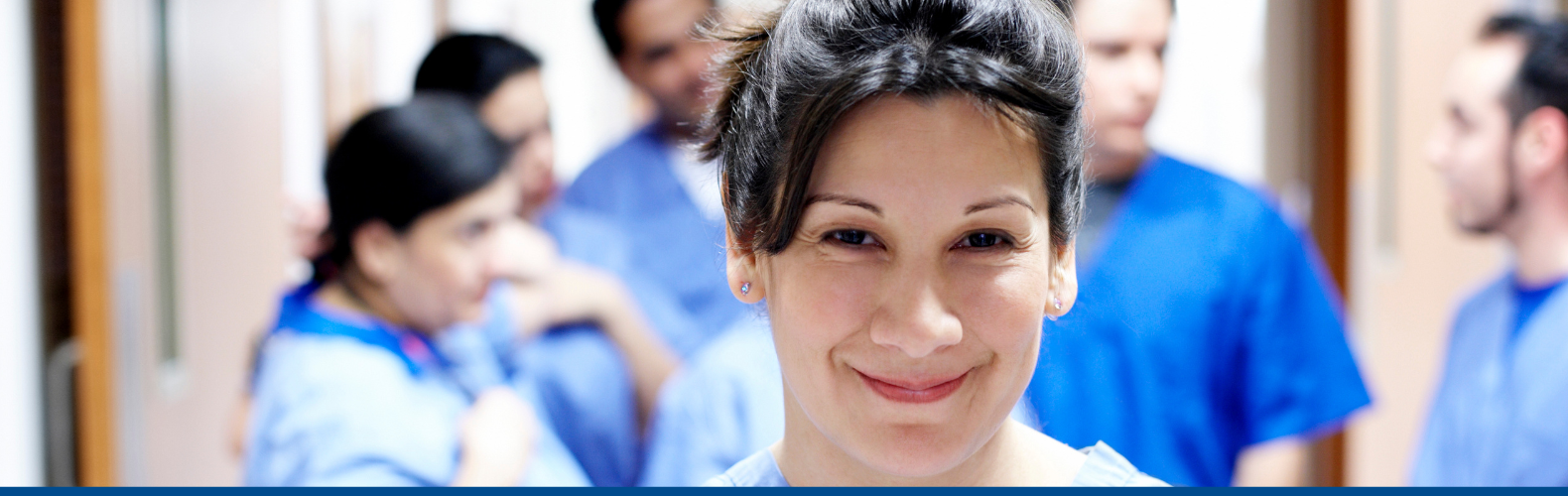 Careers at Witham, Smiling nurse in front of a group of nurses speaking in a hospital hallway