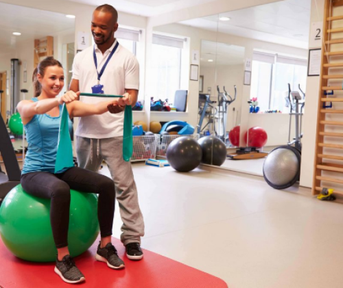 Woman sitting on therapy ball doing exercises with therapist